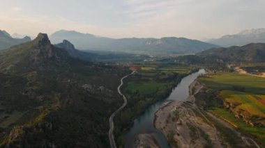 Yeşil tarlaları, çayırları, kıvrımlı dağlık nehir ve yüksek dağlı dağ sırtı ve günbatımı bulutlu gökyüzü olan hava manzarası. Türkiye 'de, Tazi kanyon bölgesinde. Sinematik İHA 4K 'yı çekiyor.