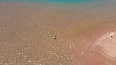 Türkiye 'nin Akdeniz kıyısındaki güzel pembe kumlu plajda yürüyen sevimli turistler üzerinde daire şeklinde bir uçuş.