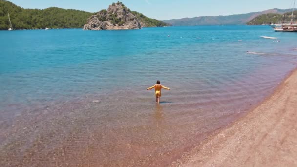 幸せな女性の上の丸ドローン飛行トルコの地中海沿岸の美しいピンクの砂のビーチと明るい美しい風景の上を歩く観光客 — ストック動画