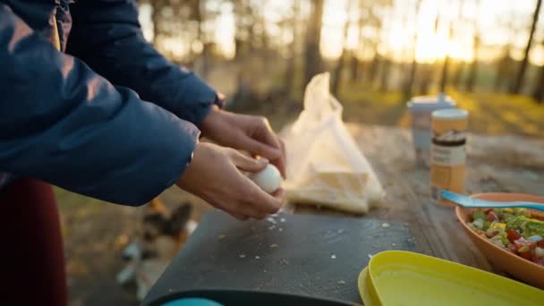 野外野餐 一个女人在外面做饭 日落时分 在秋天的森林里 为沙拉切蛋的雌性特写镜头 周末旅行和野外露营 — 图库视频影像