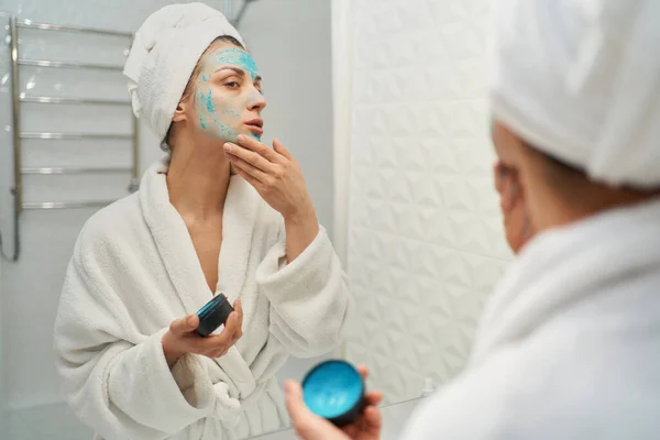 Wanita Dewasa Berdiri Depan Cermin Dengan Lembut Menerapkan Masker Wajah — Stok Foto
