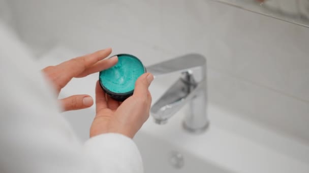 クローズアップ女性の手 トイレで指にスキンケアクリームを塗り 健康な若い女性のラップタオルを頭の上に置いた保湿フェイシャルクリーム 健康的なスキンケア治療のコンセプト — ストック動画