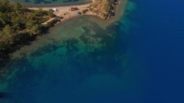 Türkiye 'de Akdeniz kıyısında arabaları ve kamyonetleriyle vahşi kamp yapmak için güzel bir hava manzarası. Minibüs turizmi yaz tatili. Ada sahilinde tenha bir sahil.