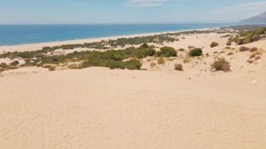 Arka planda kumlu çöl kum tepeleri ve mavi denizin çarpıcı hava manzarası. Türkiye 'de inanılmaz doğa manzarası. Patara Plajı, ünlü turistik mekan. İnsansız hava aracı görüntüleri. Türk Rivierası kıyıları.