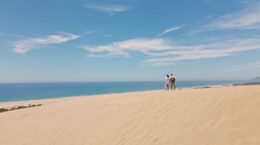 Akdeniz kıyısındaki Patara Sahili 'nde kumlu kumullarda yürüyen iki turist. Kum tepeleri, dağ sırtı ve mavi denizi olan çarpıcı bir çöl. Türkiye 'de güzel popüler bir yer