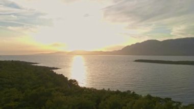 Akdeniz kıyısında günbatımında yeşil çam ormanı olan İHA uçuş sahili. Yukarıdan inanılmaz huzurlu bir manzara. Sıcak yaz günbatımında güneş, su, kayalık sahil ve ormanlarda parlar..