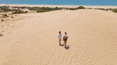 Akdeniz kıyısındaki Patara Sahili 'nde kumlu kumullarda yürüyen iki turist. Kum tepeleri, dağ sırtı ve mavi denizi olan çarpıcı bir çöl. Türkiye 'de güzel popüler bir yer