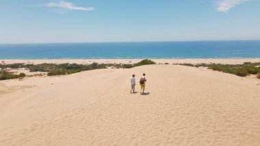 Akdeniz kıyısındaki Patara Sahili 'nde kumlu kumullarda yürüyen iki turist. Kum tepeleri, dağ sırtı ve mavi denizi olan çarpıcı bir çöl. Türkiye 'de güzel popüler bir yer