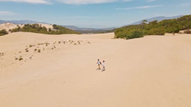 Akdeniz kıyısındaki Patara Sahili 'nde kumlu kumullarda yürüyen iki turist. Kum tepeleri, dağ sırtı ve mavi denizi olan çarpıcı bir çöl. Türkiye 'de güzel popüler bir yer