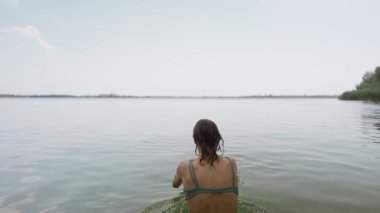 Yaz tatilinde bikinili bir kadının göle dalışının seksi bir yaz tatili. Kıçını suya daldır. Şehvetli bronzlaşmış kız dışarıda dinleniyor ve yüzüyor.
