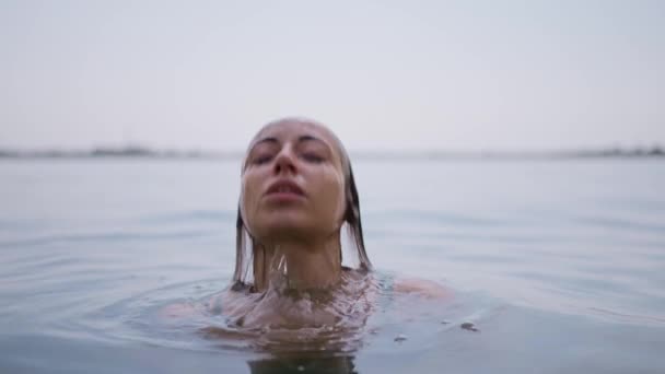 一个优雅的黑发女人的艺术形象出现在水面上 在一个慢动作的水潭里 她的脸上有青葱的波浪和擦拭的脸 — 图库视频影像