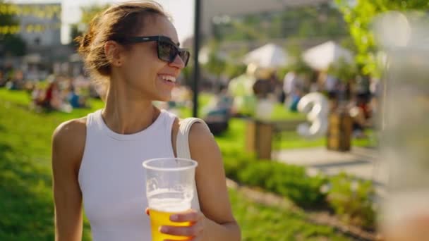 Pov幸せな喜びの若い女性は緑の牧草地の屋外のピクニックで楽しんでいます ビールでプラスチックグラスを持って 誰かと歓声を上げる女性 屋外でのパーティータイム ハッピーアワー ランチブレイク ユースコンセプト — ストック動画