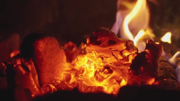 暖炉で薪炭が閉じます 暖炉の火の上の石炭のちらつき光 熱い石炭を燃やす レンガの暖炉で暖かい居心地の良い燃焼火災のクローズアップショット スローモーション — ストック動画