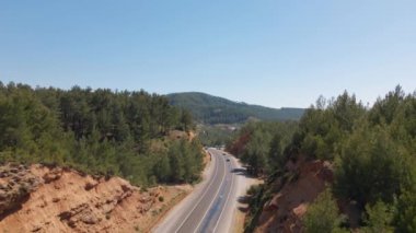 Türkiye 'de dağ yamacındaki asfalt yolun orman ve çalılarla manzarası. Ulaşım, lojistik, teslimat ve varış yerleri. Türkiye 'de seyahat, bilinmeyen yerler. Yüksek kalite 4k görüntü