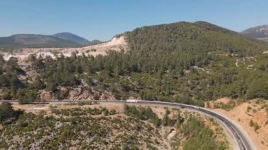 Türkiye 'de dağ yamacındaki asfalt yolun orman ve çalılarla manzarası. Ulaşım, lojistik, teslimat ve varış yerleri. Türkiye 'de seyahat, bilinmeyen yerler. Yüksek kalite 4k görüntü