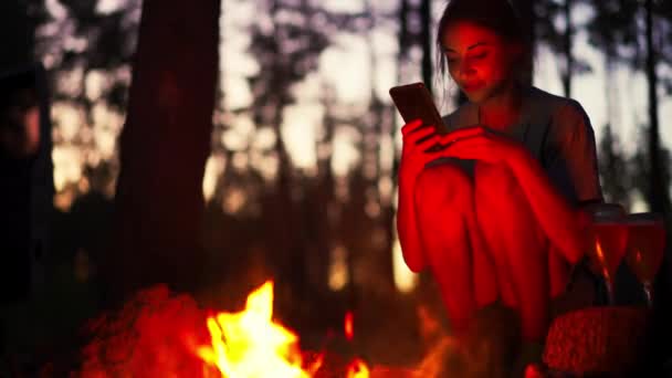 Hipster Girl Using Smartphone Sitting Next Bonfire Forest Camping Night — Stock Video