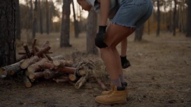 Güçlü dişi turist, ormanda akşam testeresiyle odun kesiyor. Gezgin kamp ateşi için odun hazırlıyor. Vahşi bir kadın. Doğa yürüyüşçüsü vahşi doğada hayatta kalıyor, ateş yapıyor.