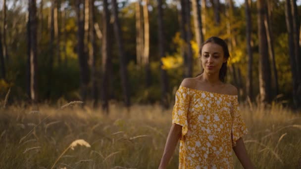秋天日落时 穿着黄色衣服 肩膀张开 在松林中散步的单身女性形象 美丽可爱的女孩在户外散步很开心 — 图库视频影像