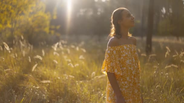 주위를 노란색 선드레스에 소녀는 자연과 혼자되는 즐깁니다 아름다움을 녹음을 슬로우 — 비디오