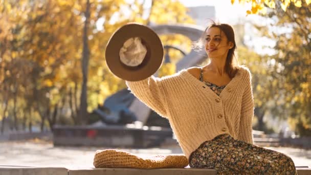 穿着衣服 毛衣和帽子的美丽微笑的女人的秋天画像 黄色叶背的女孩看着摄像机 — 图库视频影像