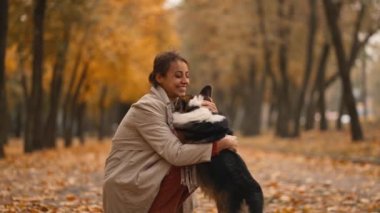 Yavaş çekim: Sevimli, zarif, zarif bir kadın, sıcak bir günde, altın rengi sonbahar akçaağaç parkında, şirin sosisli sandviçiyle dışarıda yürüyor.,