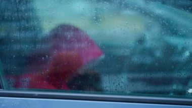 Şehirde sonbahar yağmuru altında kapüşonlu kırmızı ceketli birinin silueti arabada oturuyor. Su damlalarıyla pencereden ateş ediyorlar. Şiddetli yağışlı mevsim, soğuk yağış