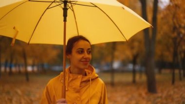 Sarı şemsiyeli kız. Ağır çekim yağmur parkı. Şemsiyenin altında saklanan genç bir kadın. Çamurlu yürü. Sağanak yağmur. Kötü bulutlu hava. Kadınlar ıslak caddede yürürler.