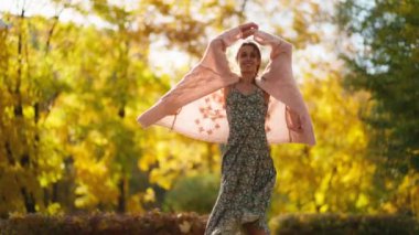 Güneşli sonbahar parkında güzel, mutlu bir genç kız. Güneş ışınlarıyla dönen bir kadın. Kadın doğanın tadını çıkarıyor ve eğleniyor. Sonbahar parkında boş zaman. Sonbahar havası