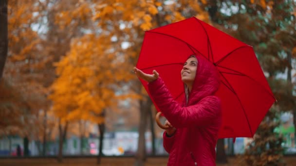 赤い傘の下に隠れていた女性は 雨の日にオレンジ色の市立公園の雨の下を一人で歩いていました スローモーションショット 秋の季節と都市生活 — ストック動画