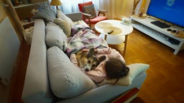 Evcil hayvanını kucaklayan genç bir kadının portresi. Şirin Galli Corgi köpeği sahibinin yanında dinleniyor, evde birlikte vakit geçiriyorlar. Köpek ve insanla arkadaşlığı kavra, tatlı anlar, rahatlatıcı, kaygısız