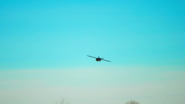 スローモーションドローンが空の背景に向かって飛んでいる 飛行機型のドローンがフィールド上空を飛んでいる 軍用ドローン — ストック動画