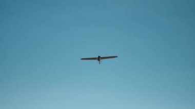 Ağır çekim askeri hava aracı mavi gökyüzünün arka planında uçuyor. Uçak şeklinde bir dron karada uçuyor. askeri İHA