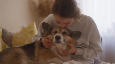 Kadın kanepeye uzanır, Galli Corgi 'si bacaklarının üzerinde yatarken gülümser. Köpeği okşar ve ona sarılır, onunla nazikçe sohbet ederken sevgi dolu anları paylaşır. Konforlu ev kurmak, paylaştıkları bağ ve mutluluğu vurguluyor