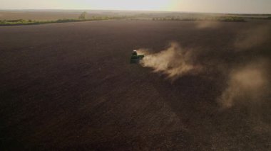 Gün batımında tarlada çalışan traktörün hava gözlem dronu, altın ışık. Tarım sektörü konsepti. Küçük tarım kavramı. Çekici disk harrow tarlayı sürüyor. Sonbahar, hasat ve tohum ekme