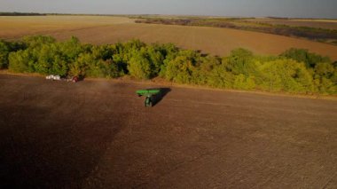Gün batımında tarlada çalışan traktörün hava gözlem dronu, altın ışık. Tarım sektörü konsepti. Küçük tarım kavramı. Çekici disk harrow tarlayı sürüyor. Sonbahar, hasat ve tohum ekme