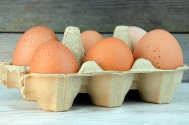 Tahta masadaki kutuda altı kahverengi tavuk yumurtası.