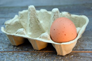 Tahta masadaki kutuda kahverengi benekli tavuk yumurtası.