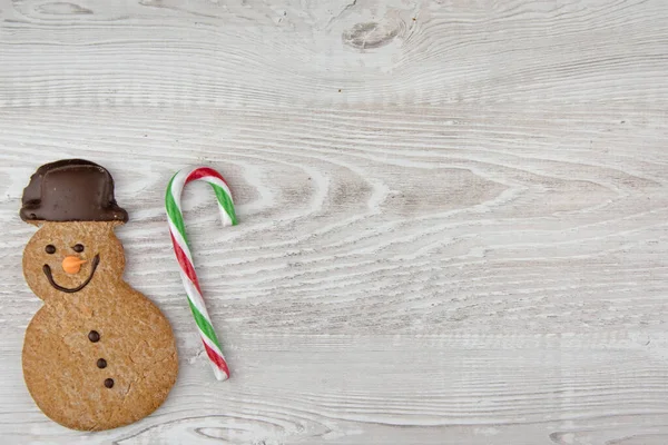 トップ表示のクリスマスクッキーとともにジンジャーブレッド男上の光木製の背景 — ストック写真