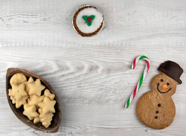 トップ表示のクリスマスクッキーとともにジンジャーブレッド男上の光木製の背景 — ストック写真