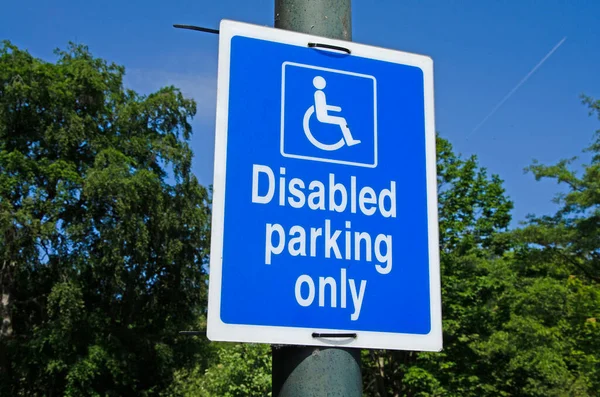 stock image Sign board for disabled parking on a lamp pole. Blue skies