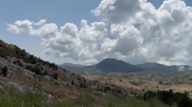 Tepeler ve dağlardan oluşan bulutlu bir arabanın penceresinden bir manzara. Yüksek kalite 4K görüntü