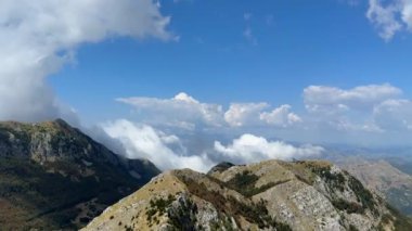 Karadağ 'da dağdan dağa, kabarık bulutlu mavi gökyüzü. Rocky bitki örtüsüyle zirve yapıyor. Varış yeri. Yüksek kalite 4K görüntü