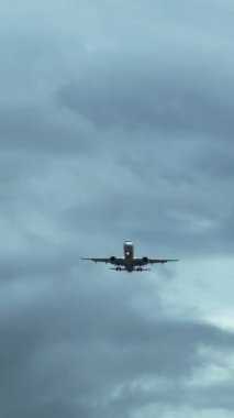 Üstümüzde uçan bir yolcu uçağının alt görüntüsü. Bulutlu gökyüzünde, hava araçlarının iniş takımlarını yakın çekimde açın. Yüksek kalite 4K görüntü