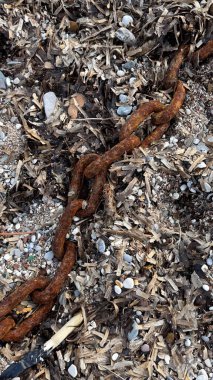 Fırtınadan sonra çakıl taşlı plajda paslı zincirlerin geniş halkalarını yakın çekim. Yüksek kaliteli fotoğraflar. 
