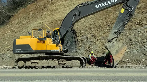 Budva, Karadağ - 9 Nisan 2025: Budva - Tivat karayolu onarımı. İşçiler kazıcının yanında dinleniyor. Yüksek kaliteli fotoğraflar