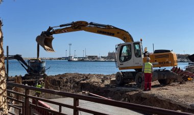 Budva, Karadağ-11 Nisan 2025: Liebherr ve Volvo kazıcıları, arka planda işçiler ve bir marinayla birlikte bir deniz kenarı şantiyesinde. Yüksek kalite fotoğraf