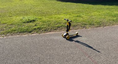 Budva, Karadağ-11 Nisan 2025: Park yolunda sarı çocuk scooter 'ının yakın çekimi. Yüksek kalite fotoğraf