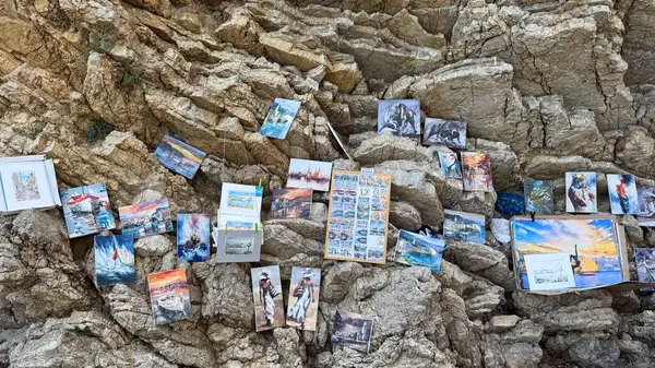 Budva, Karadağ - 18 Mayıs 2025: Mogren Sahili yakınlarındaki kayalık bir uçurumda çeşitli resim ve manzaraların sergilendiği bir sanat sergisi.