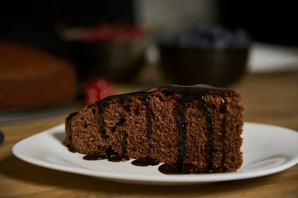 木製のキッチンテーブルの上にクランベリーと赤スグリで飾られた手作りのチョコレートケーキ ストック写真
