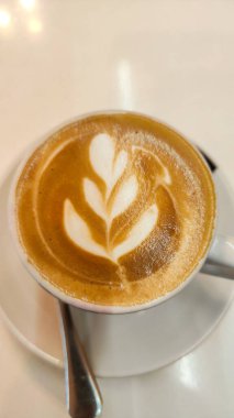 Özgün bir şekilde seçici bir odak ile bir çiçek çizim ile kremalı latte kupa